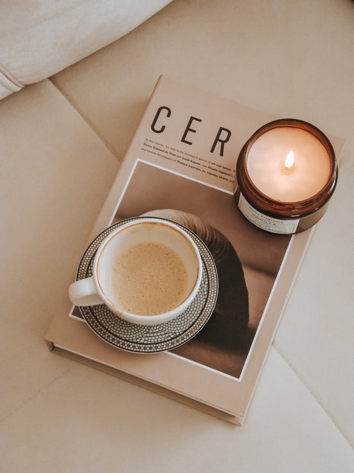 Warm and inviting flat lay with coffee, candle, and magazine showcasing hygge lifestyle.